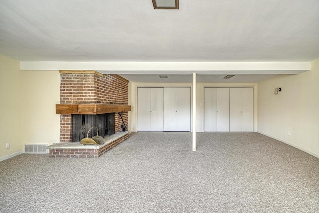 unfurnished living room with carpet flooring, a fireplace, visible vents, and baseboards