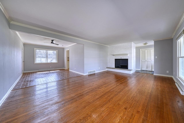 unfurnished living room featuring baseboards, wood finished floors, visible vents, and ornamental molding