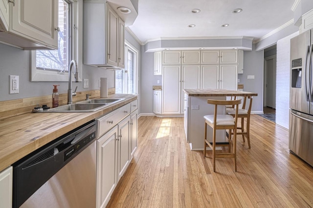 kitchen with a sink, ornamental molding, butcher block countertops, and stainless steel appliances