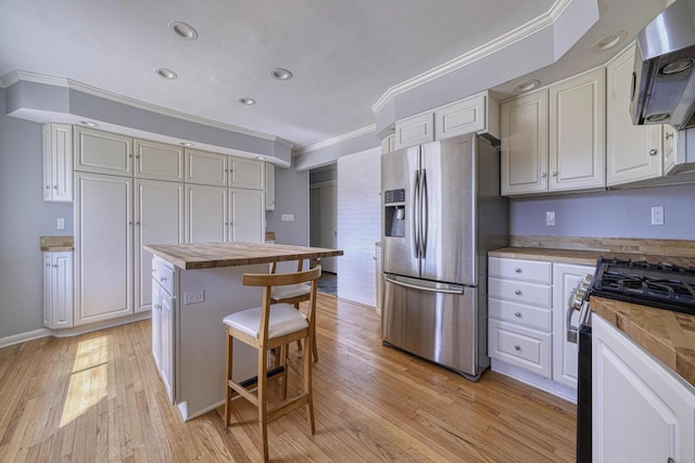 kitchen featuring ventilation hood, butcher block counters, gas range oven, light wood-style floors, and stainless steel fridge