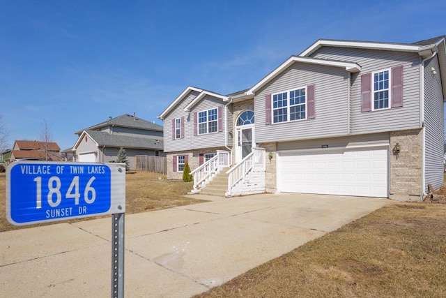 split foyer home featuring concrete driveway, an attached garage, and brick siding