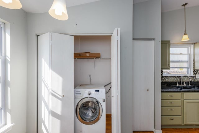 laundry area featuring laundry area, washer / dryer, light wood-type flooring, and a sink