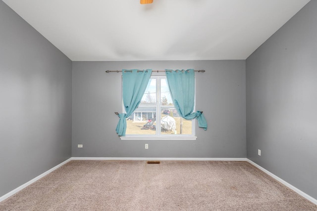 carpeted spare room with visible vents and baseboards