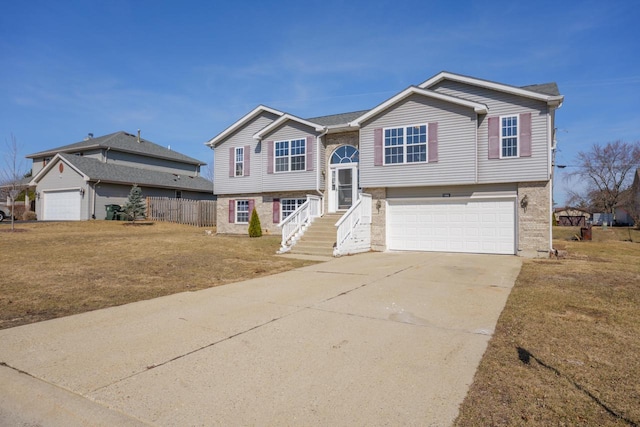 raised ranch with brick siding, a garage, a front lawn, and driveway