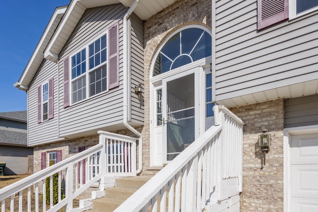 doorway to property with a garage and brick siding