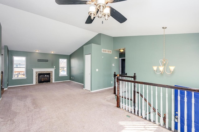 interior space with carpet, visible vents, baseboards, lofted ceiling, and ceiling fan with notable chandelier