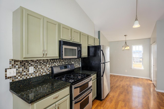 kitchen with lofted ceiling, stainless steel appliances, pendant lighting, light wood-type flooring, and backsplash