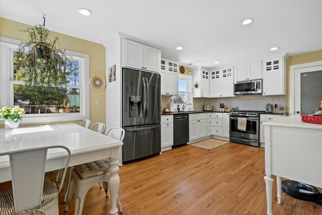 kitchen featuring light wood-style flooring, recessed lighting, stainless steel appliances, white cabinets, and decorative backsplash