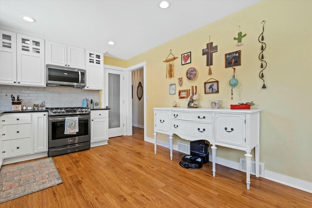 kitchen with visible vents, stainless steel appliances, white cabinetry, tasteful backsplash, and light wood-type flooring