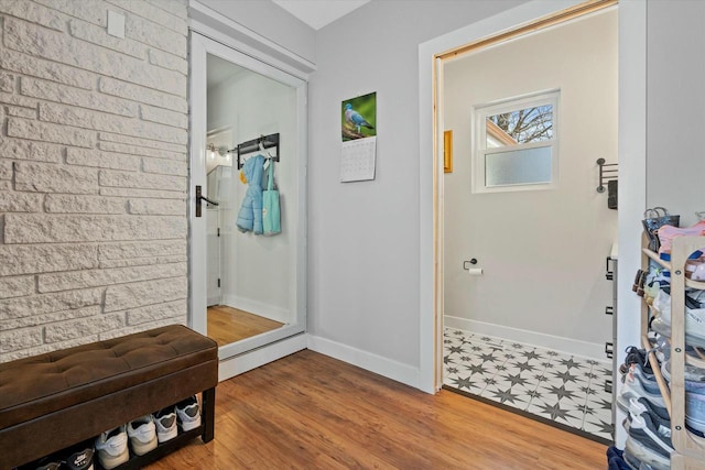 mudroom featuring baseboards, wood finished floors, and brick wall