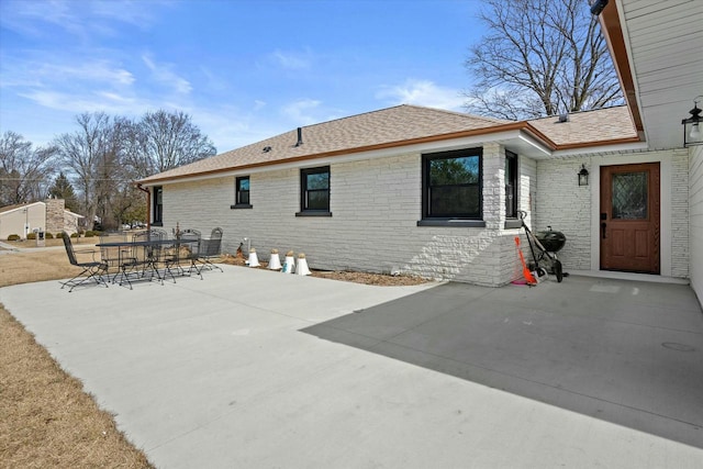 back of house with a patio, brick siding, outdoor dining space, and a shingled roof