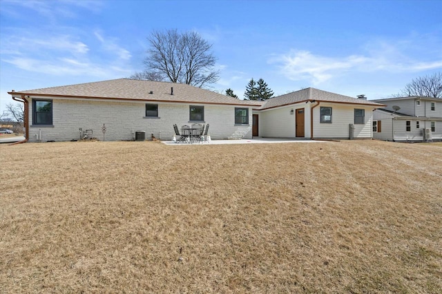 back of house featuring brick siding, central AC, a lawn, and a patio area