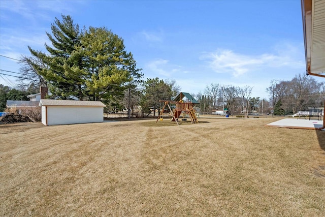 view of yard with a garage, an outbuilding, and a playground