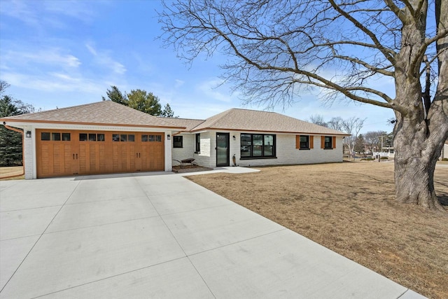 view of front of property featuring brick siding, driveway, a shingled roof, and a garage