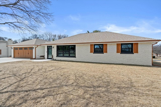 ranch-style house with concrete driveway, an attached garage, a front lawn, and a shingled roof