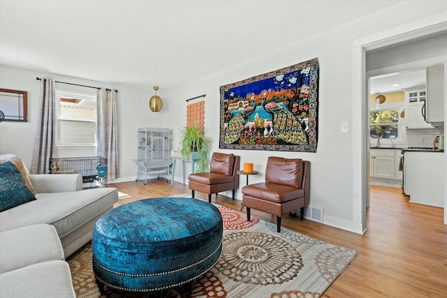 living room with light wood finished floors, visible vents, plenty of natural light, and baseboards