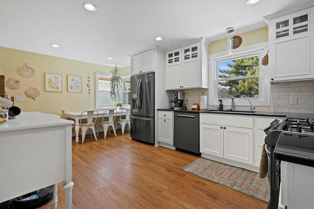 kitchen featuring gas range, light wood-type flooring, black dishwasher, stainless steel fridge, and a sink