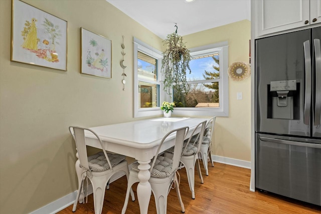 dining space featuring baseboards and light wood finished floors