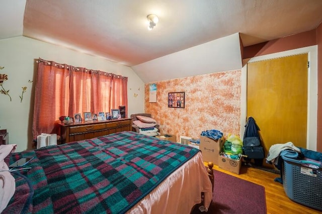 bedroom featuring wallpapered walls, wood finished floors, and vaulted ceiling