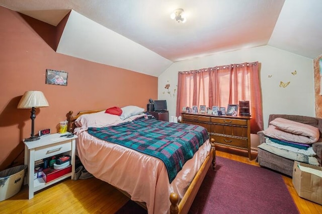 bedroom with lofted ceiling and wood finished floors