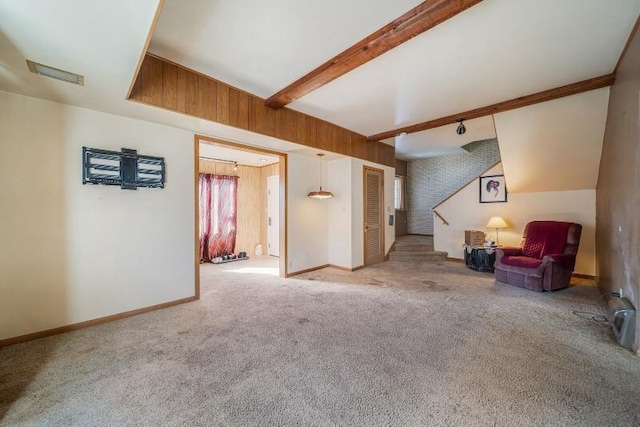 interior space with baseboards, visible vents, carpet floors, wood walls, and beamed ceiling