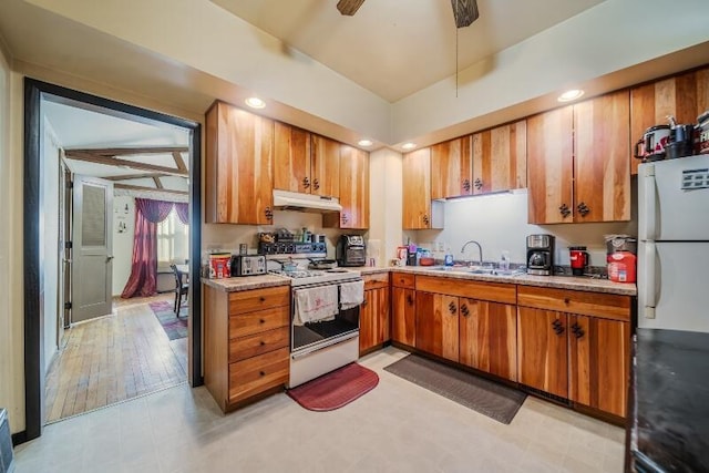 kitchen with under cabinet range hood, light countertops, brown cabinets, white appliances, and a sink