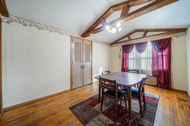 dining area featuring lofted ceiling with beams, baseboards, a chandelier, and hardwood / wood-style flooring