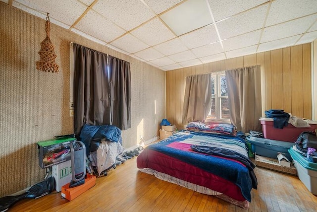 bedroom featuring a drop ceiling and hardwood / wood-style floors