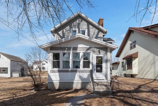 view of front of home with entry steps and a chimney