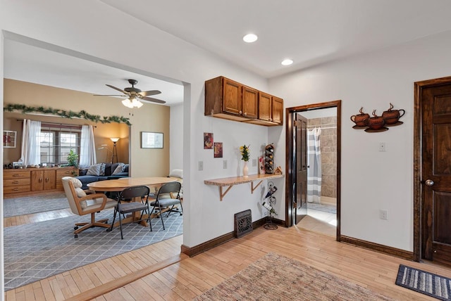 kitchen featuring brown cabinetry, visible vents, baseboards, light wood-style flooring, and ceiling fan