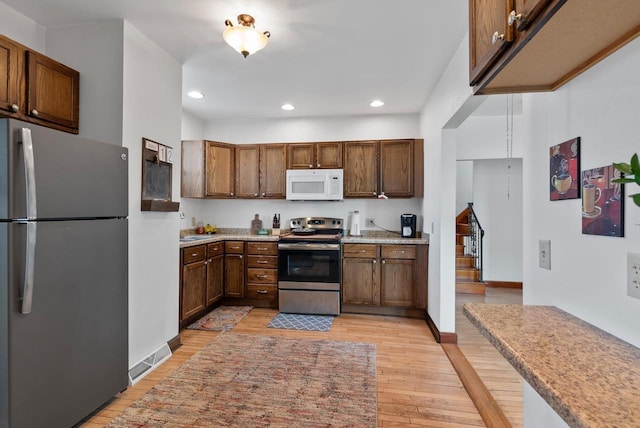 kitchen with baseboards, light wood finished floors, recessed lighting, light countertops, and appliances with stainless steel finishes