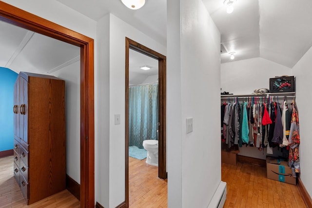 spacious closet featuring hardwood / wood-style floors, lofted ceiling, and baseboard heating