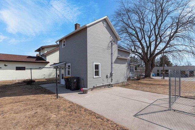 rear view of house with a patio, a chimney, and fence