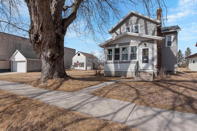 view of front of property featuring entry steps, an outbuilding, and a chimney