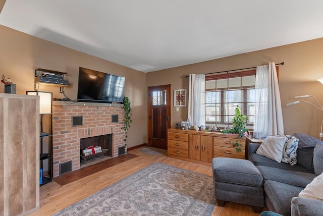 living area with visible vents, a brick fireplace, and wood finished floors