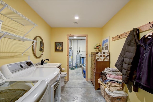 laundry room with a sink, washing machine and dryer, water heater, and laundry area