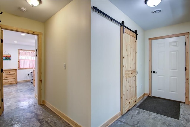 foyer entrance with a barn door, baseboards, visible vents, and concrete flooring