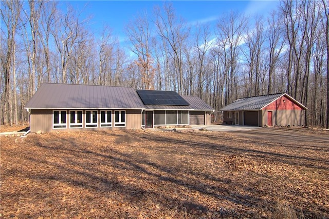 exterior space with an outbuilding, solar panels, metal roof, and a garage