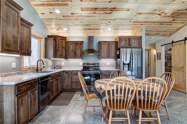 kitchen with a sink, a barn door, appliances with stainless steel finishes, wall chimney range hood, and lofted ceiling