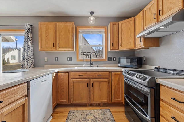 kitchen with black microwave, under cabinet range hood, double oven range, white dishwasher, and a sink