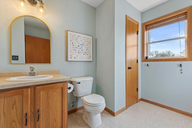 half bath with vanity, toilet, and baseboards