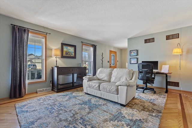 living room with baseboards, visible vents, and a textured ceiling