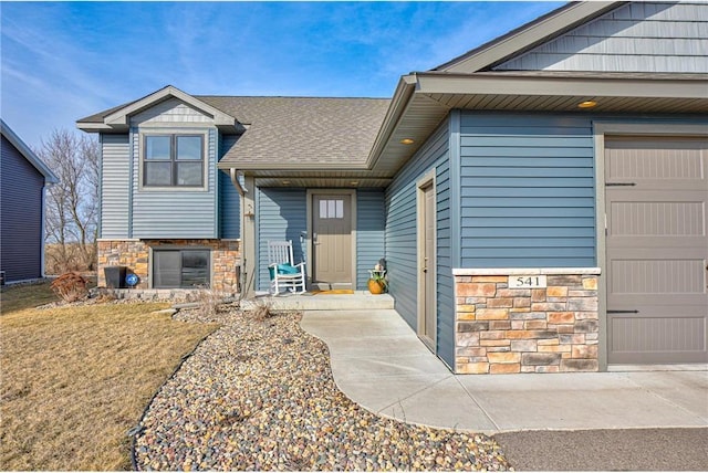 doorway to property featuring stone siding and a shingled roof