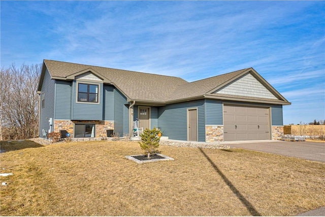 view of front of home with stone siding, driveway, roof with shingles, and an attached garage