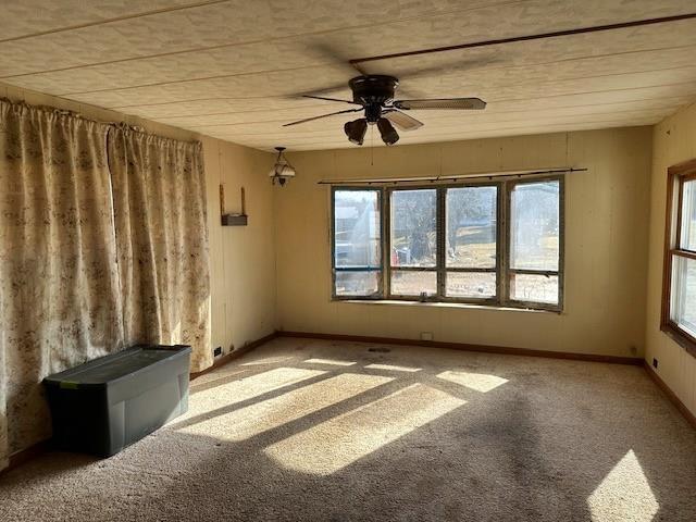 unfurnished room featuring baseboards, carpet, and a ceiling fan