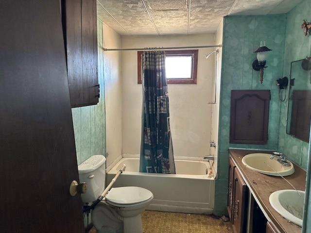 bathroom featuring double vanity, shower / bathtub combination with curtain, toilet, and a sink