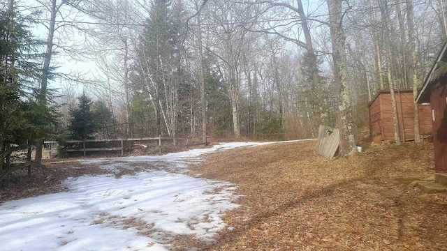 yard layered in snow featuring a forest view