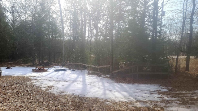 yard layered in snow with a forest view and an outdoor fire pit