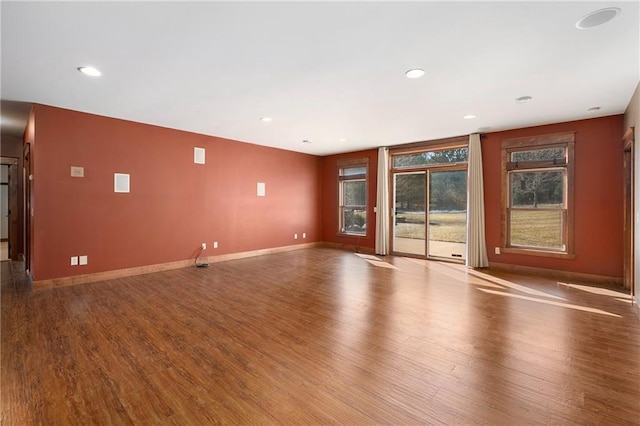 unfurnished living room with recessed lighting, wood finished floors, and baseboards