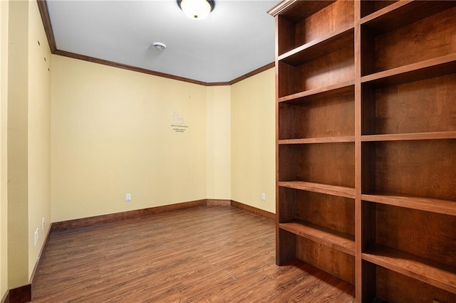 empty room with crown molding, wood finished floors, and baseboards